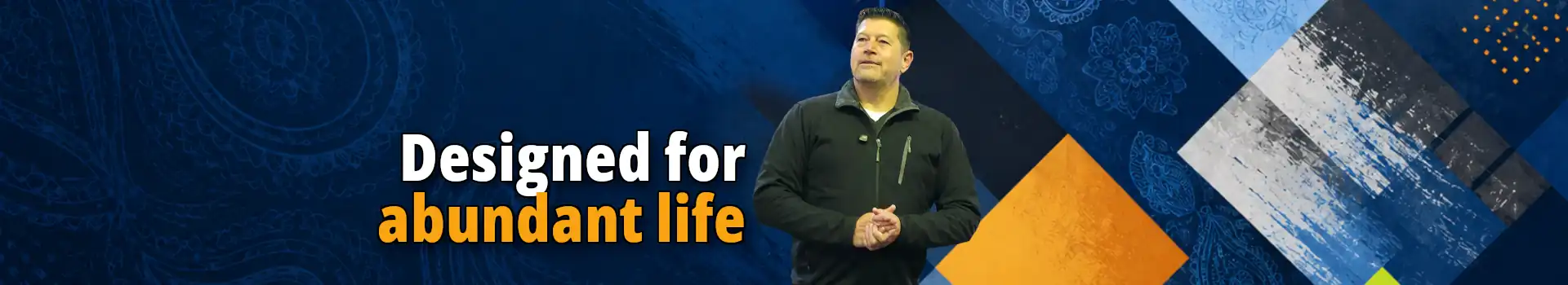 John Veitch presenting a Spiritual Reset message against a blue geometric background with the text 'Designed for abundant life'.